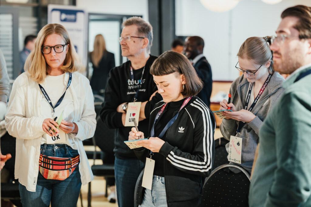 Eine Gruppe von Menschen die während einer Session Post-Its nehmen und Inhalte für den Workshop erstellen